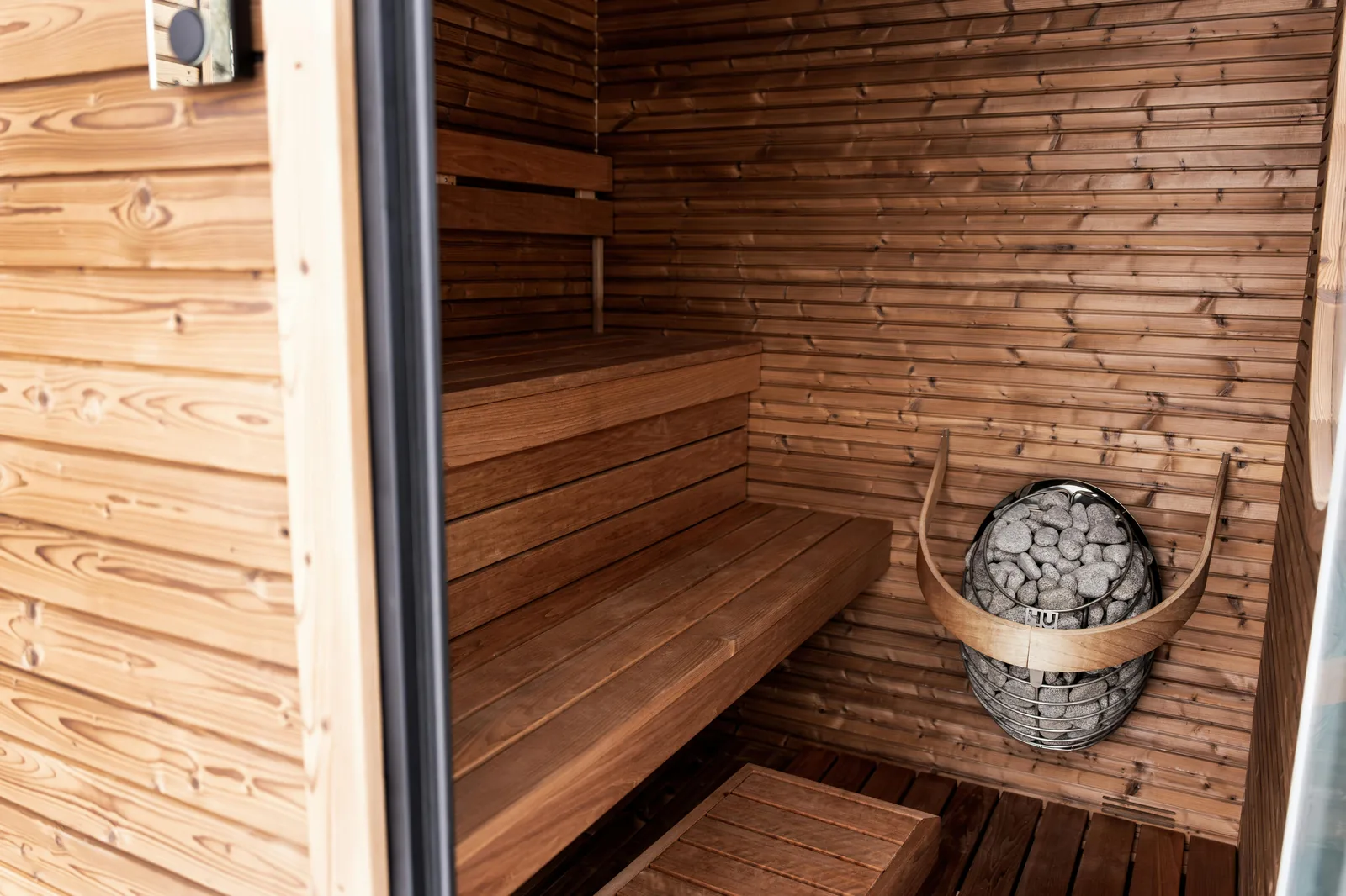 A sauna bucket and ladle inside a warm cedar sauna