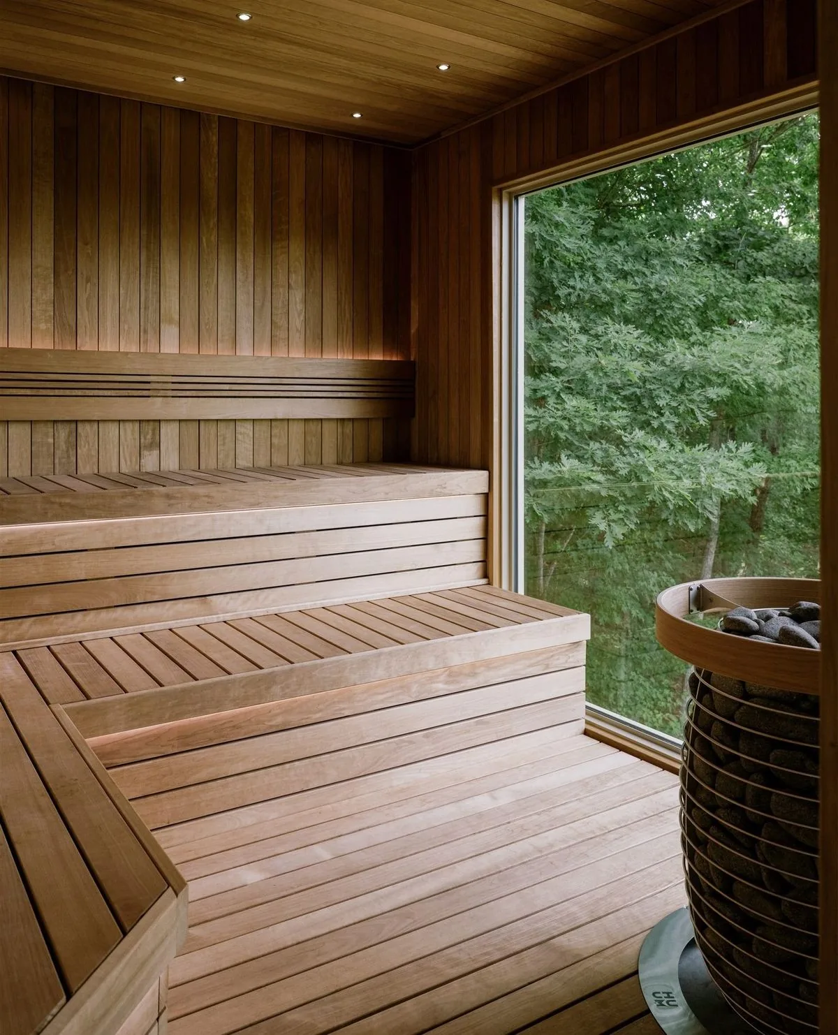 A cedar sauna interior with a forest view